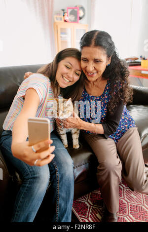 Großmutter und Enkelin nehmen Selfie mit Katze auf sofa Stockfoto