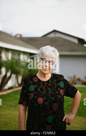 Ältere Frau mit Händen auf den Hüften im Hinterhof
