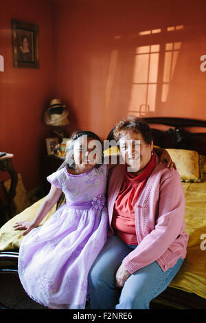 Hispanische Großmutter und Enkelin sitzt auf Bett Stockfoto