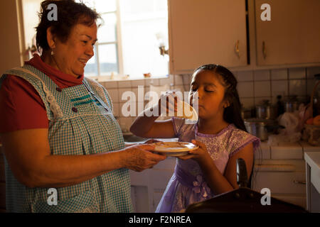 Hispanic Frau kochen für Enkelin in Küche Stockfoto