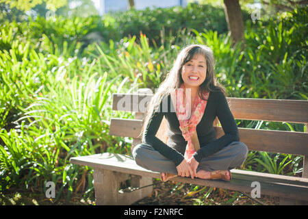 Japanische Frau sitzt auf der Parkbank Stockfoto