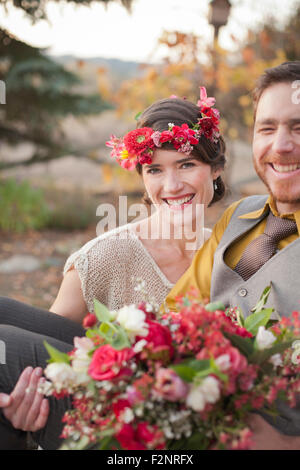 Braut trägt Bräutigam und Strauß im ländlichen Bereich Stockfoto