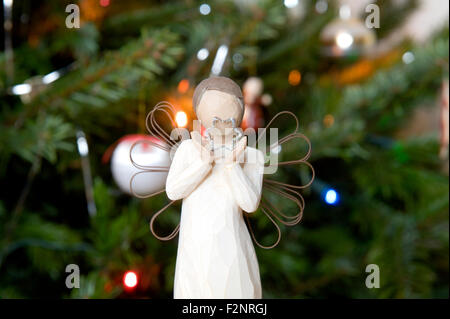 Ein festliches Bild eines Engels hält eine Sternform vor einer traditionellen echten Tanne Weihnachten Stockfoto