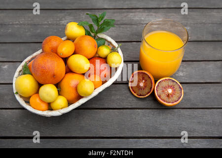 Zitrusfrüchte und Orangensaft in einen hölzernen Hintergrund. Orangen, Limetten, Mandarinen, chinesischen Orangen, Blutorangen... Stockfoto