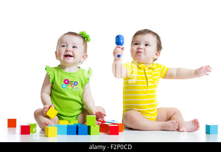 Zwei entzückende Babys spielen mit Spielzeug. Kleinkinder-Mädchen und jungen am Boden. Isoliert auf weißem Hintergrund. Stockfoto