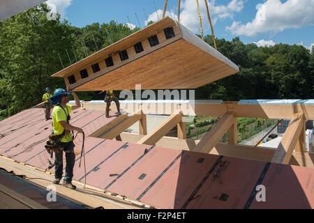 Bauarbeiter installieren Dachplatten auf Leed Platin Common Ground High School Gebäude. Stockfoto