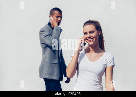 Porträt der lächelnde junge Frau telefonieren mit Smartphone vor Youn Mann Stockfoto