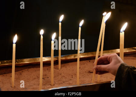 Hand anzünden von Kerzen in der Kirche Stockfoto