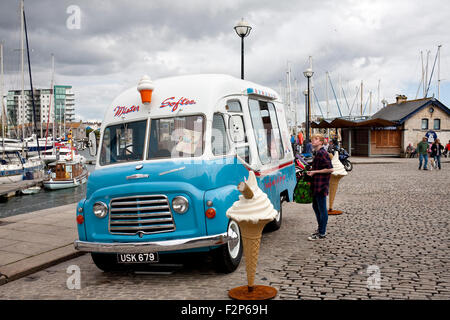 Kauf von einem Mister Softee 1960,s Commer Karrier Eiswagen auf dem gepflasterten Kai Sutton Harbour, Plymouth männlich Stockfoto