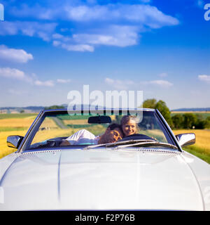Mann, der auf der Schulter der weiblichen Fahrerin beim Fahren eines Mercedes-Cabrios auf Landstraßen, im Elsass, in Frankreich und in Europa schlagt Stockfoto
