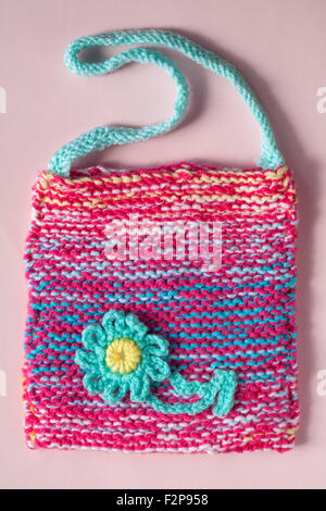 Rosa und blaue gestrickte Tasche mit Daisy Blume auf rosa Hintergrund isoliert Stockfoto