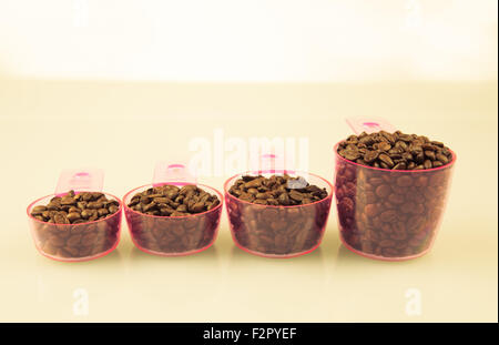 Kaffeebohnen im Messbecher in verschiedenen Größen. Stockfoto