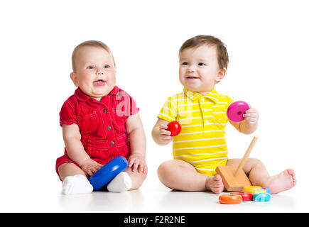 Zwei entzückende Kinder mit Spielzeug zu spielen. Kleinkinder-Mädchen und jungen am Boden. Isoliert auf weißem Hintergrund. Stockfoto