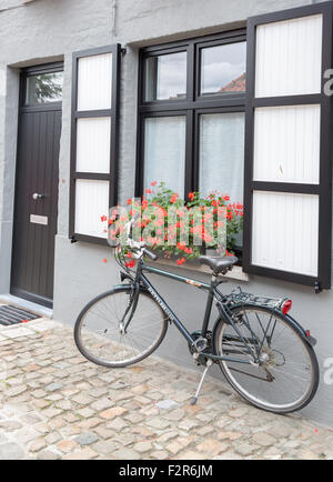 Ein Fahrrad geparkt gegen ein Fenster zur Straße von Brügge in Belgien Stockfoto