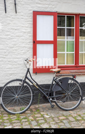 Ein Fahrrad geparkt gegen ein Fenster zur Straße von Brügge in Belgien Stockfoto