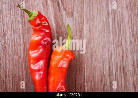 Zwei frische rote scharfe Chilischoten auf einem hölzernen Hintergrund für text Stockfoto