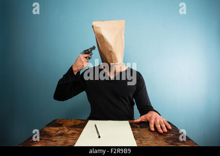 Mann mit Papiertüte über dem Kopf dreht sich nach dem Schreiben eines Briefes Stockfoto