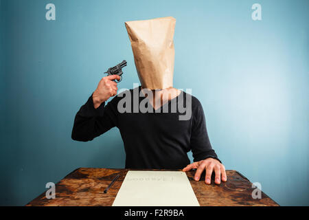 Mann mit Papiertüte über dem Kopf dreht sich nach dem Schreiben eines Briefes Stockfoto