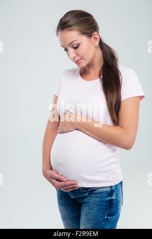 Porträt einer schwangeren Frau streichelt ihren Bauch isoliert auf weißem Hintergrund Stockfoto