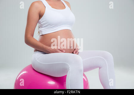 Closeup Portrait einer schwangeren Frau sitzen auf einer Fitness-Ball auf einem weißen Hintergrund isoliert Stockfoto