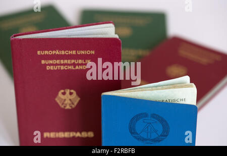 Berlin, Deutschland. 20. Sep, 2015. Eine blaue Personalausweis aus der ehemaligen DDR (R) und einen deutschen Pass (L) aufrecht in einer Tabelle vor eine Reihe von ehemaligen westdeutschen Travel Pässe in Berlin, Deutschland, 20. September 2015. Foto: Soeren Stache/Dpa/Alamy Live News Stockfoto