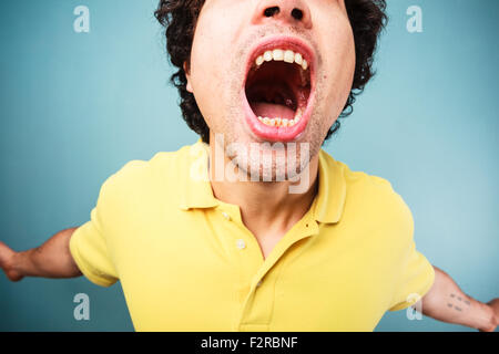 Junger Mann schreit mit weit geöffnetem Mund Stockfoto
