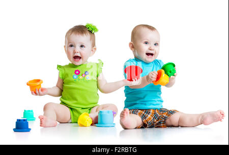 Entzückende Babys spielen mit Farbe Spielzeug. Kinder Mädchen und jungen am Boden. Isoliert auf weißem Hintergrund. Stockfoto