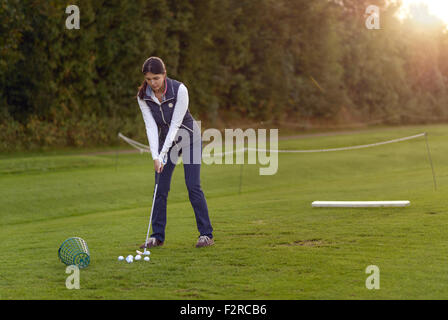 Golfspielerin stehen auf der driving Range am späten Nachmittag am Tag, für den nächsten Schlag konzentrieren Stockfoto