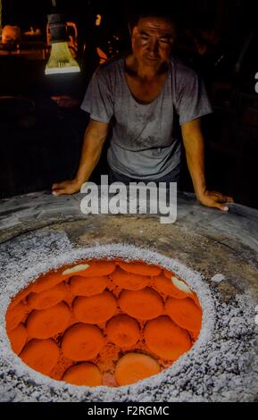 (150923)--TURPAN, 23. September 2015 (Xinhua)--Foto am 16. September 2015 zeigt Abduweli Rozi warten auf das Backen von Nang, eine Art von knusprigem Brot, in seiner Werkstatt in Turpan, Nordwesten Chinas Xinjiang Uygur Autonome Region. Fast jeden frühen Morgen 45-Year-Old Abduweli Rozi und seine Frau vor 03:00 aufwachen und beginnen ihre Arbeit. In den nächsten 10 Stunden würden sie 300 Nang zu machen und zu den Verkäufern in der Stadt verteilen. Dies ist nur ein Teil der Geschichte, die jeden Tag in einer kooperativen Gruppe von Nang Entscheidungsträger in Turpan nahm. Neben Abduweli Rozis Gruppierungsfunktion zusammenarbeiten 17 Familien, ich Stockfoto