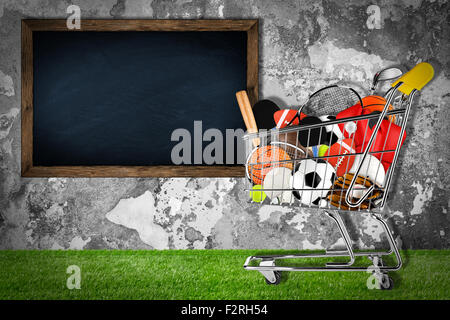 Warenkorb gefüllt mit Sportgeräten vor Steinmauer mit blackboard Stockfoto