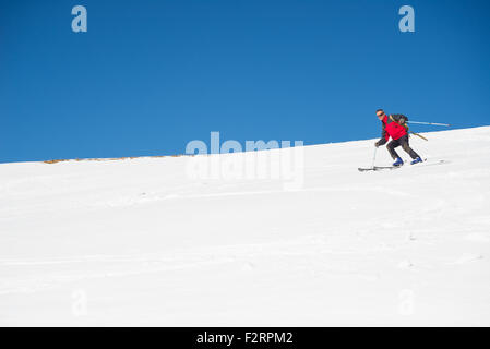 Eine Person, die Ski Abfahrten auf verschneiten Hang in malerische Skigebiet der Alpen, mit hellen, sonnigen Tag Ende Wintersaison Stockfoto