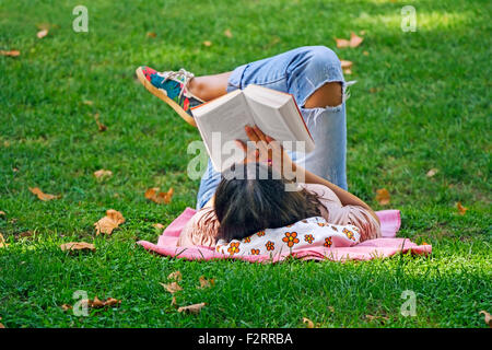 Junges Mädchen ein Buch in dem Rasen im Park liegen Stockfoto