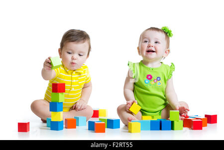 Zwei entzückende Kinder mit Spielzeug zu spielen. Kleinkinder-Mädchen und jungen am Boden. Isoliert auf weißem Hintergrund. Stockfoto