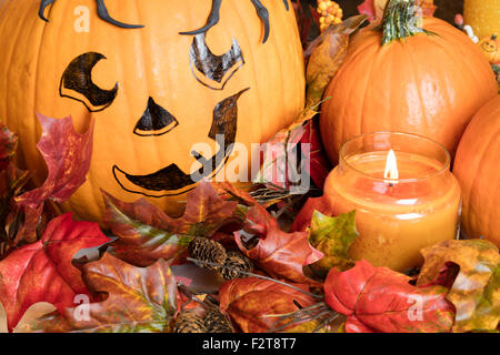 Bemalten Kürbis Gesicht mit Zucker Kürbisse und eine brennende Kerze für eine Halloweendekoration einrichten Stockfoto