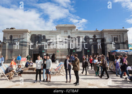 Besucher im Inneren Banksy Dismaland stehen vor einem Gebäude mit dem Wort malte Mediocre drauf von Axel Void. Stockfoto