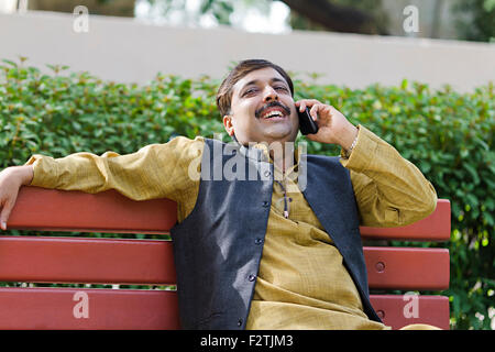 1 indische erwachsenen Mannes sitzen Parkbank Handy im Gespräch Stockfoto