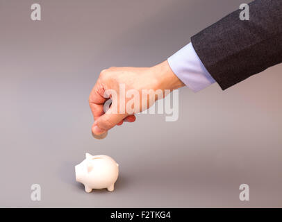 Mans Hand Münze ins Sparschwein, isoliert auf grauem Hintergrund einfügen Stockfoto