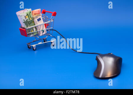 Konzept des e-shopping. Warenkorb mit Euro und Computer-Maus auf blauem Hintergrund isoliert Stockfoto
