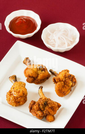 Detailansicht der würzigen Backhendl Lutscher mit Tomatenketchup und rohe Zwiebel Saiten serviert. Flachen DOF. Stockfoto