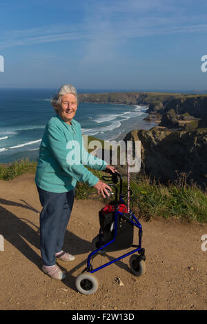 Aktive Dame Rentner mit 3-Rad Trolley Mobilitätshilfe von schönen Küste Szene Bedruthan Schritte Cornwall uk Stockfoto