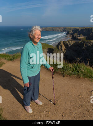 Rentner aktiv alte Dame mit Gehstock von schönen Küste Szene Bedruthan Schritte Cornwall uk Stockfoto