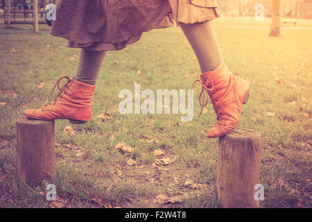 Eine Frau ist spielerisch auf einige kleine Holzpfosten im Park spazieren. Stockfoto
