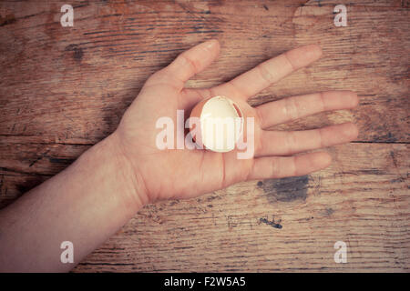Ein Mann hält eine Eierschale in seiner Hand an einem Tisch Stockfoto