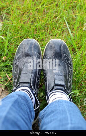 Schuss schwarze Turnschuhe mit weißen und schwarzen Streifen Socken auf dem Rasen Stockfoto