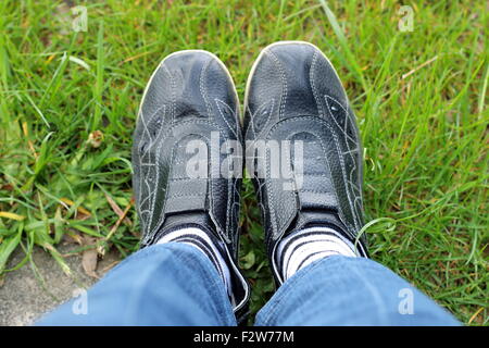 Schuss schwarze Turnschuhe mit weißen und schwarzen Streifen Socken auf dem Rasen Stockfoto