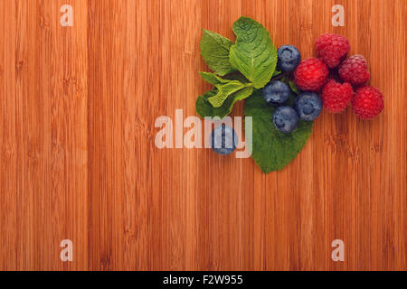 Vorgeschmack auf den Sommer, Schneidbrett mit mellow Blaubeeren, Himbeeren und Minze Stockfoto