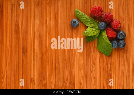 Vorgeschmack auf den Sommer - Schneidebrett mit mellow Blaubeeren, Himbeeren und Minze – fügen Sie Ihren text Stockfoto