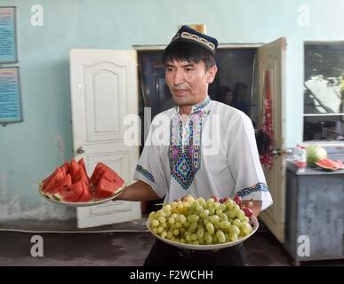 (150924)--TURPAN, 24. September 2015 (Xinhua)--Pataer Keyimu dient dazu frisches Obst, Kunden zu Hause in der Traube Tal von Turpan, Nordwesten Chinas Xinjiang Uygur Autonome Region, 6. September 2015. Pataer führt im Vergleich mit dem Leben seines Großvaters, eine neue Art des Lebens durch nicht nur Anbau und Verkauf von Trauben, aber auch Tourismus und andere Unternehmen dank des Internets. Im Jahr 2010 Pataer ein Aufenthalt mit der Familie Unternehmen gegründet und verkauft lokale Produkte wie getrocknete Trauben, um Touristen anzuziehen. In diesem Jahr, schätzt er, dass die jährlichen Ertrag 150.000 RMB Yuan (etwa 23.505 US-Dollar) erreichen würde. Wie das 3G Stockfoto