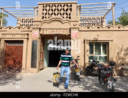 (150924)--TURPAN, 24. September 2015 (Xinhua)--Pataer Keyimu geht aus seinem Haus in der Traube Tal von Turpan, Nordwesten Chinas Xinjiang Uygur Autonome Region, 6. September 2015. Pataer führt im Vergleich mit dem Leben seines Großvaters, eine neue Art des Lebens durch nicht nur Anbau und Verkauf von Trauben, aber auch Tourismus und andere Unternehmen dank des Internets. Im Jahr 2010 Pataer ein Aufenthalt mit der Familie Unternehmen gegründet und verkauft lokale Produkte wie getrocknete Trauben, um Touristen anzuziehen. In diesem Jahr, schätzt er, dass die jährlichen Ertrag 150.000 RMB Yuan (etwa 23.505 US-Dollar) erreichen würde. Als der 3G Service von Stockfoto