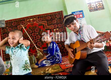 (150924)--TURPAN, 24. September 2015 (Xinhua)--Pataer Keyimu spielt Gitarre zu Hause in der Traube Tal von Turpan, Nordwesten Chinas Xinjiang Uygur Autonome Region, 6. September 2015. Pataer führt im Vergleich mit dem Leben seines Großvaters, eine neue Art des Lebens durch nicht nur Anbau und Verkauf von Trauben, aber auch Tourismus und andere Unternehmen dank des Internets. Im Jahr 2010 Pataer ein Aufenthalt mit der Familie Unternehmen gegründet und verkauft lokale Produkte wie getrocknete Trauben, um Touristen anzuziehen. In diesem Jahr, schätzt er, dass die jährlichen Ertrag 150.000 RMB Yuan (etwa 23.505 US-Dollar) erreichen würde. Als der 3G Service von Stockfoto